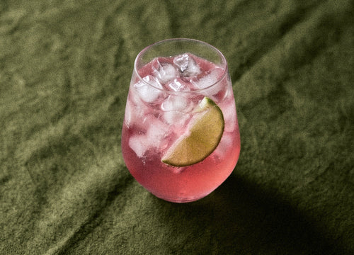 Pink Pop cocktail made with Humdinger Pink Gin, served over ice with a lime wedge on green linen