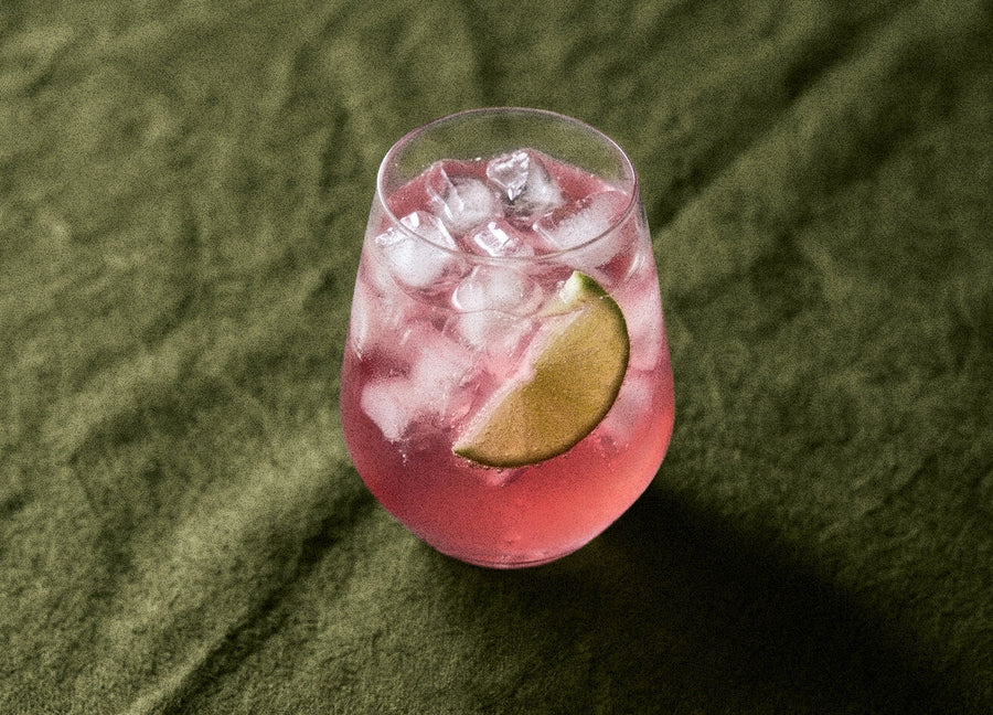 Pink Pop cocktail made with Humdinger Pink Gin, served over ice with a lime wedge on green linen